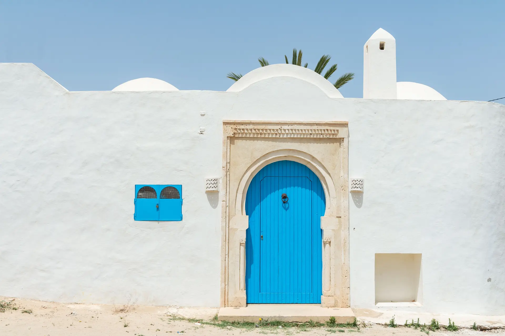 White plaster wall with an arched blue door