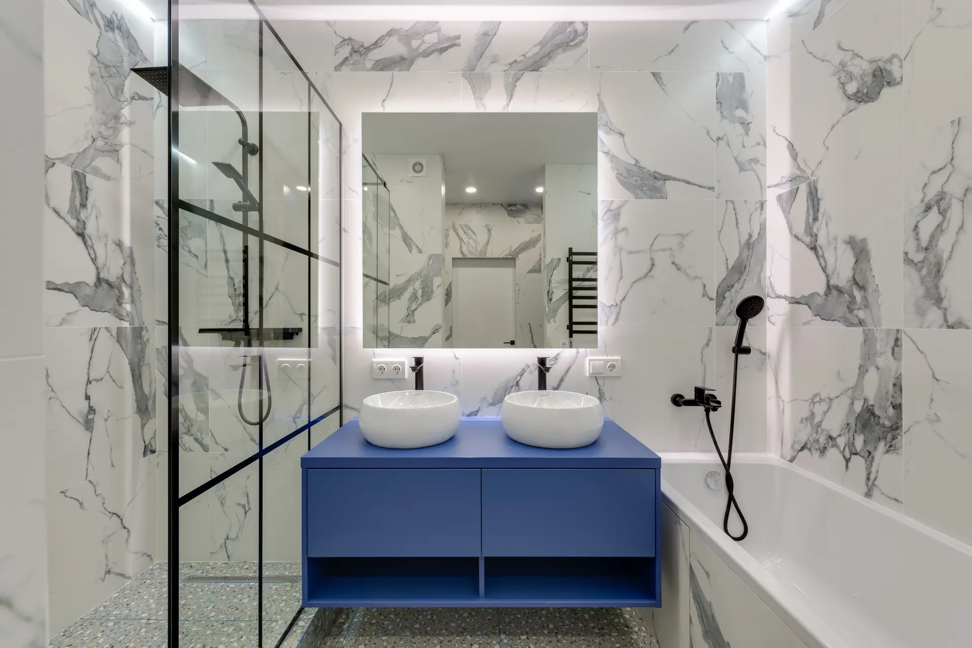 Bathroom with marble tile, a glass shower and a blue vanity