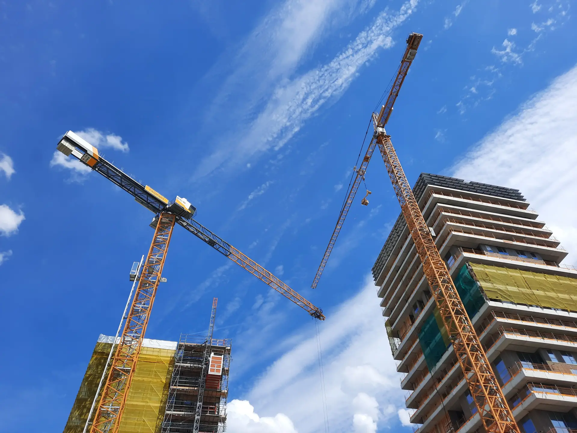 Cranes beside a high-rise under construction