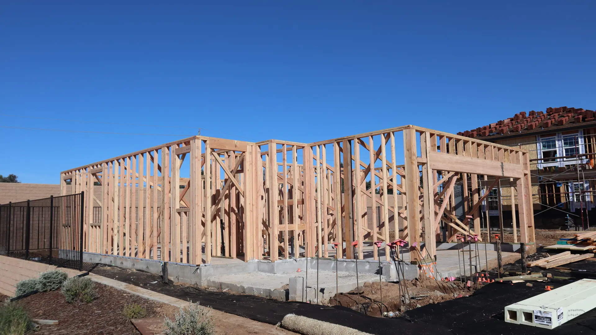 New wall framing standing on a fresh concrete foundation