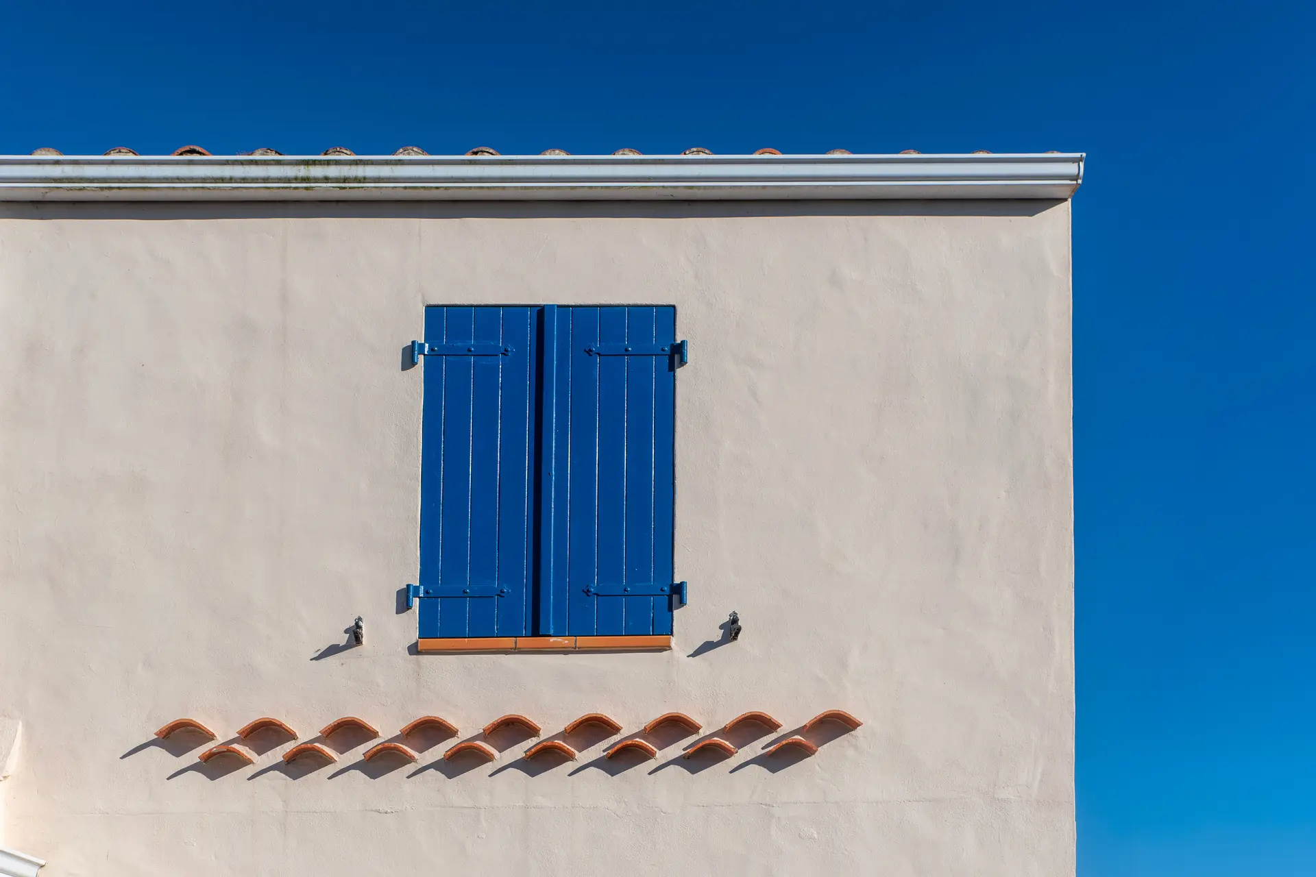Smooth white stucco wall with blue window shutters